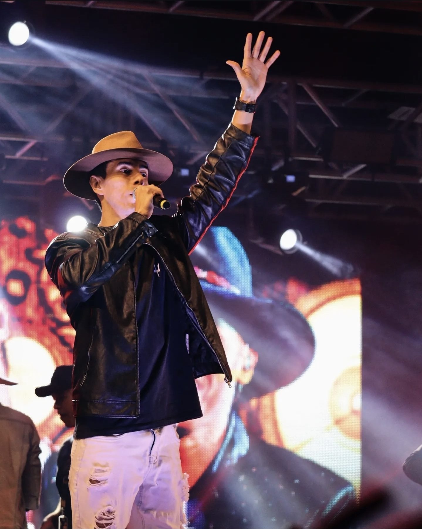 Anderson Junior de chapéu cantando no palco