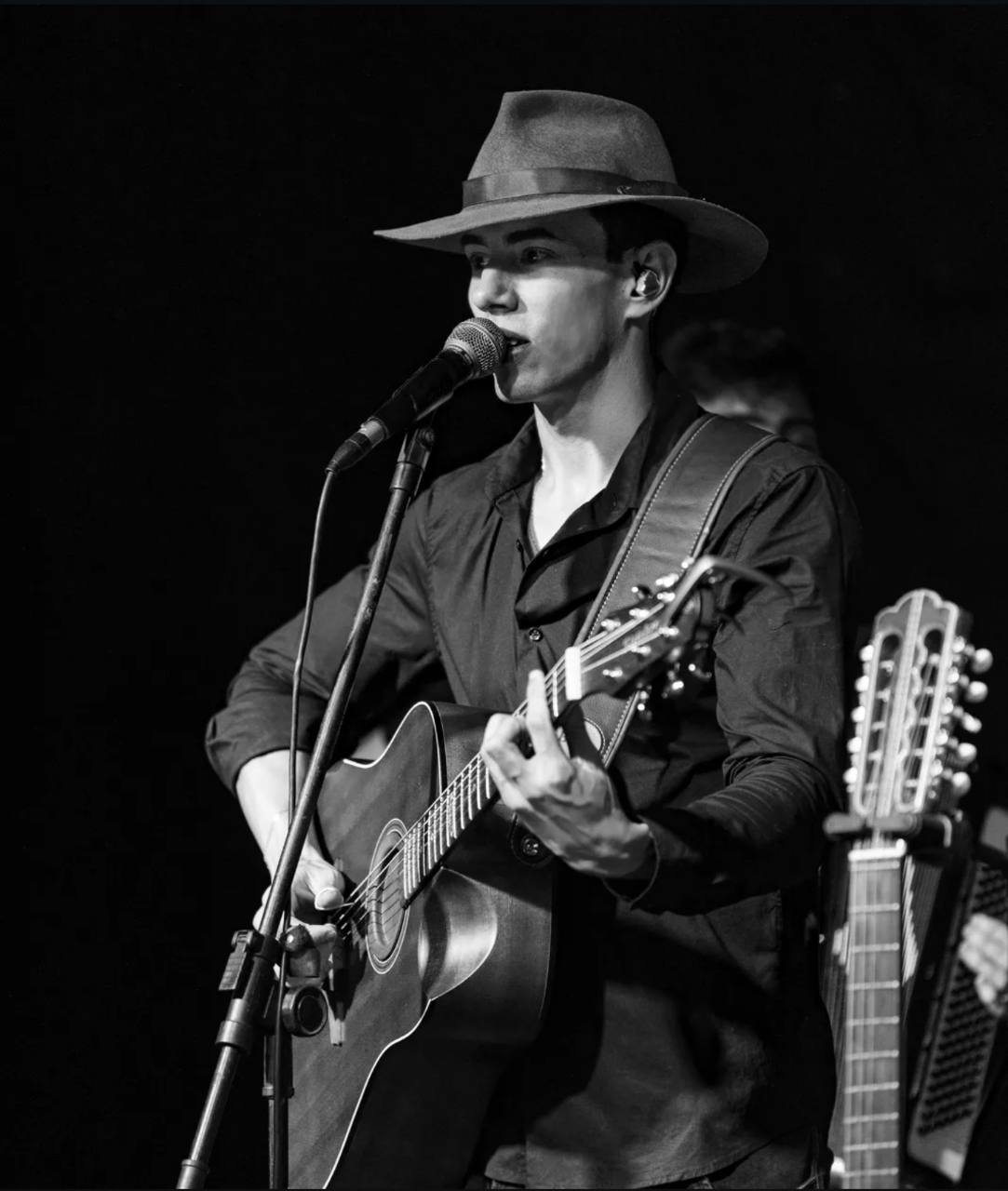 Anderson Junior de chapéu cantando e tocando violão em preto e branco