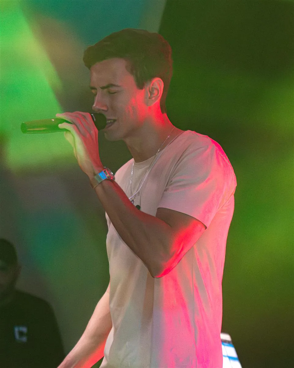 Anderson Junior cantando ao microfone sob luzes de palco